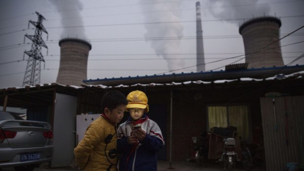 Boys look at a phone next to a coal-fired power plant on the outskirts of Beijing in November.