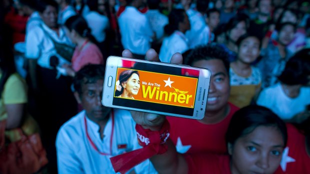 An NLD supporter displays her mobile phone as a crowd gathered to celebrate unofficial election results outside the party's headquarters in Yangon on Monday. 