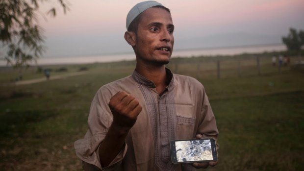 Osman Gani, a Rohingya man from Myanmar, shows a video clip that he shot on his mobile phone as he describes the recent violence standing on the bank of the Naf River, near a camp for Rohingyas near Cox's Bazar, Bangladesh.