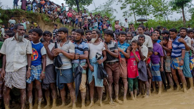 Rohingya Muslim men, who crossed over from Myanmar into Bangladesh, wait for their turn to collect food at a refugee camp.