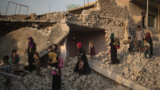 Women and children flee through the rubble of destroyed houses in the Old City of Mosul on Tuesday.