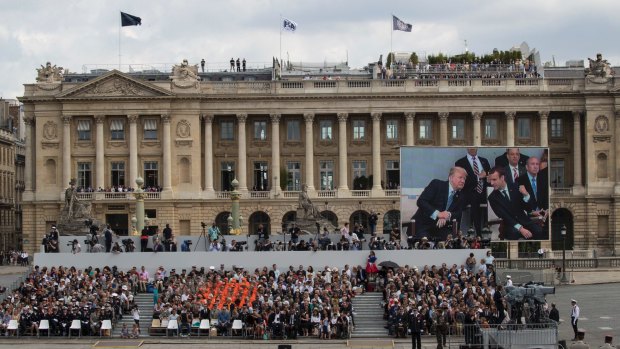 US President Donald Trump and French President Emmanuel Macron are seen on a large screen during Bastille Day parade on the Champs Elysees avenue in Paris.