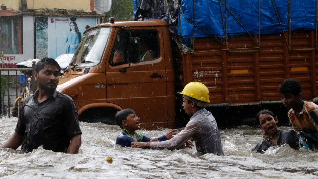 Children play in a waterlogged street during heavy rains in Mumbai.