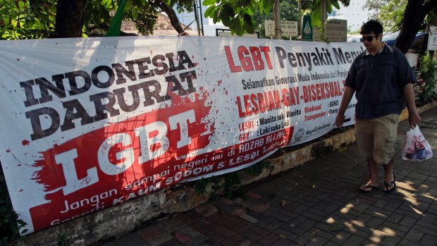 A man walks past an anti-LGBTI banner erected by an ultra-conservative Islamic group in Jakarta. Indonesia's Constitutional Court is considering whether to make gay sex a crime after accepting a judicial review petition from Islamic activists. 