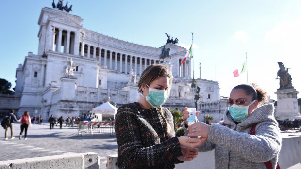 Women wearing face mask disinfect their hands in central Piazza Venezia in Rome.