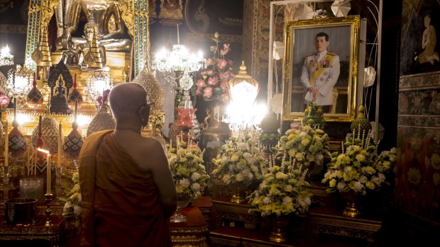 A monk prays in front of the portrait of His Majesty King  Rama X on Thursday.