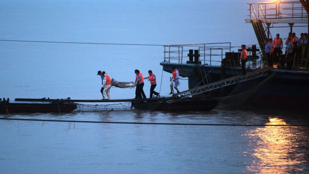 Rescue workers carry a body from the capsized passenger ship, where hundreds remain unaccounted for. 