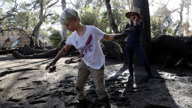 Jennifer Markham, right, and her son Peter walk in the mud in Montecito, California.