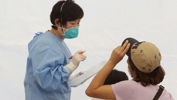 A nurse talks with a woman and child in a tent used as a waiting room for people being tested for MERS.