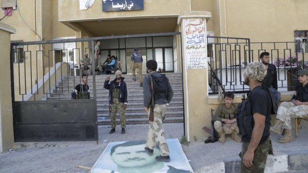 Rebel fighters walk on a poster of Syrian President Bashar al-Assad in the north-western city of Ariha. The rebel groups that took Ariha, in Idlib province, are now on the defensive in Aleppo province.