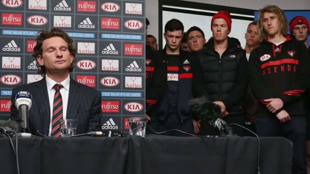 The end of the road: James Hird announcing his resignation as Essendon coach, watched by the players.