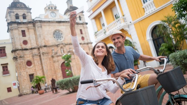 Tourists pose for a photo in front of Colonial architecture typical of Cartagena, Colombia.