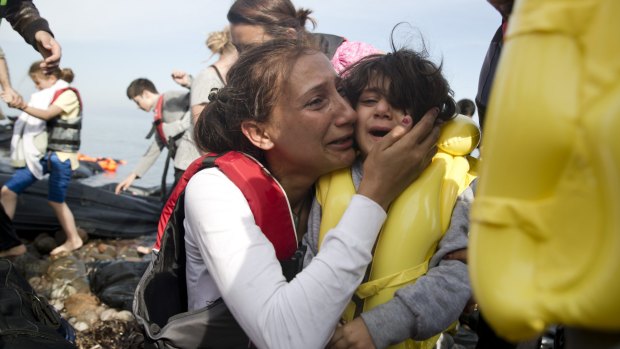 A Syrian woman and her child react after they arrived with others from Turkey on the shores of the Greek island of Lesbos, on a inflatable dinghy on Sunday.