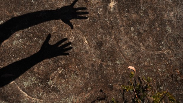 A silhouette of Nathan Moran's hands on a moon engraving next to Baiane's boomerang on Moon Rock.