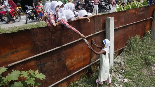 Schoolchildren hand out food to a young Rohingya girl at a temporary shelter in Aceh.