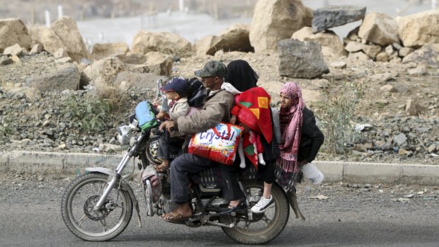 A man flees with his family and their belongings on a motorcycle in Sanaa, Yemen.