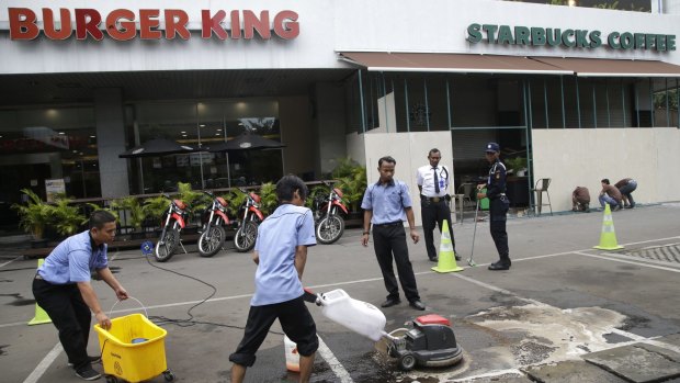 Workers clean up the spot outside Starbucks in central Jakarta where militants were killed.