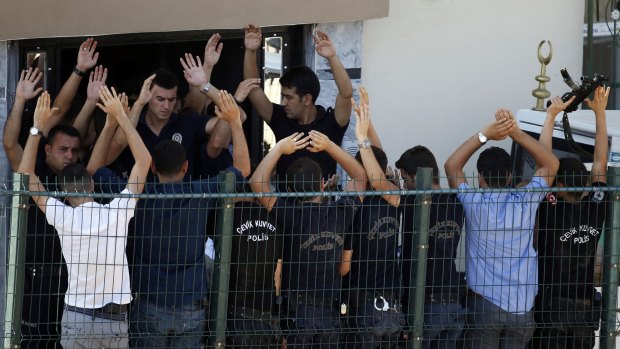 Police officers raise their hands in a bid to prevent media from taking photos of the officers' coffins being carried into a funeral vehicle.