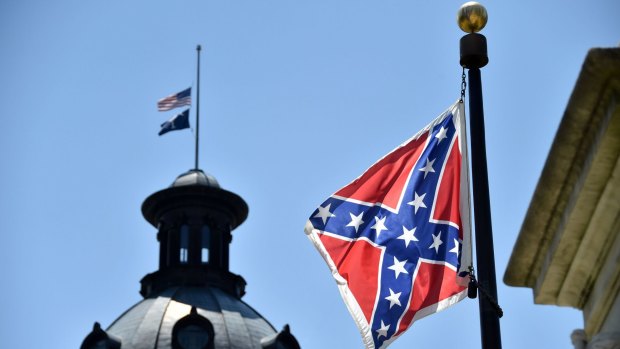 The South Carolina and American flags flying at half-mast behind the Confederate flag at the State Capitol building in Columbia, South Carolina on Friday.