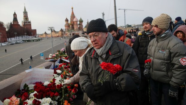 People lay flowers at a portrait of Russian opposition leader Boris Nemtsov at the place where he was gunned down, in Moscow.
