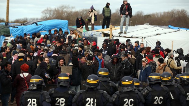 Police officers face activists and migrants in the Jungle, Calais, on Monday.