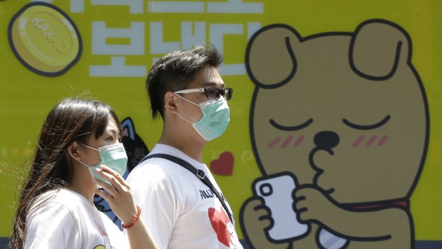 A couple wears masks as a precaution against the MERS virus as they walk on the Myeongdong, one of the main shopping districts in Seoul.