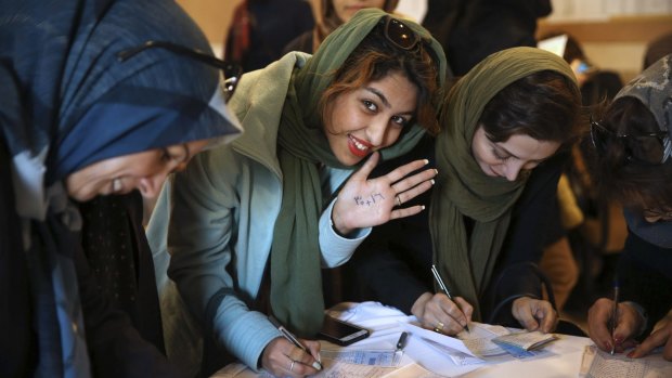 An Iranian voter shows her hand with numbers 30+16, a reformists slogan urging people to vote all reformists and moderate candidates, as she fills out her ballot in a polling station in Tehran, Iran on Friday.