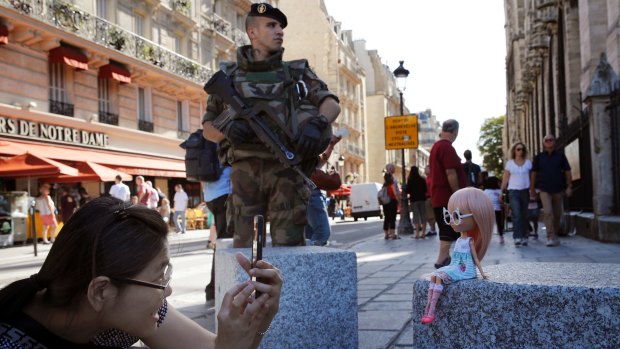 A French soldier stands guard as a tourist takes pictures of her doll in front of Notre Dame cathedral in Paris on Friday.