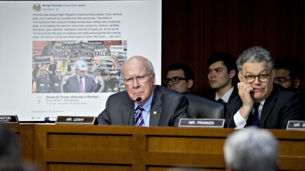A sponsored event post is displayed behind Senator Al Franken, right, and Senator Patrick Leahy during the hearing on Tuesday.