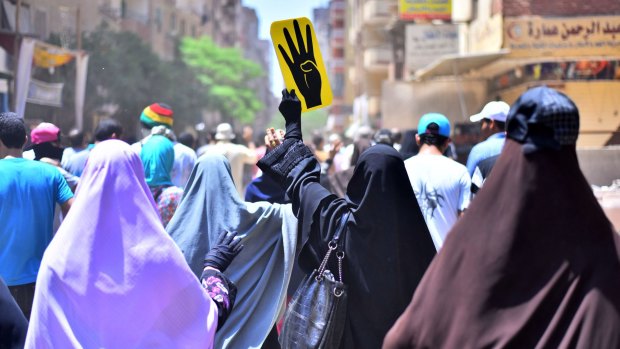 Female supporters of the Muslim Brotherhood hold up the sign of a hand with four fingers representing the massacres of protesters outside Cairo's Rabaa al-Adawiya mosque in 2013. 