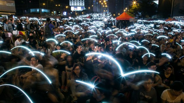 Demonstrators wave their mobile devices as part of the protest outside government offices in Hong Kong.