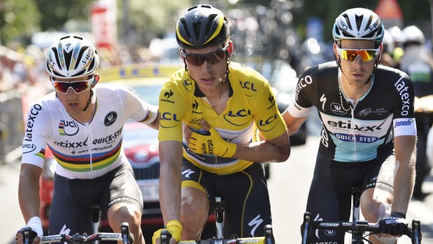 Germany's Tony Martin, wearing the overall leader's yellow jersey, is accompanied by his teammates after breaking his collarbone.