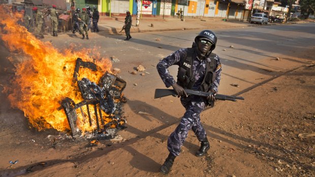 A Ugandan riot policeman runs past a burning barricade left by angry supporters of opposition leader Kizza Besigye on Monday. 