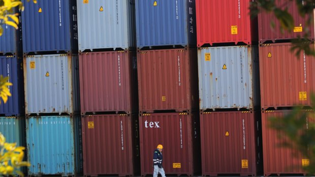 A port worker walks past a pile of cargo at a container terminal in Tokyo. Japan is experiencing sluggish exports.