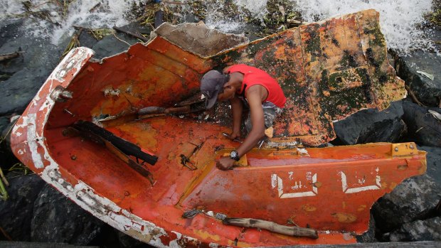 Filipino Joybin Marayo, 58, salvages metals on a damaged boat that was washed ashore by strong waves brought about by typhoon Haima in Manila.
