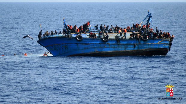 People try to jump before their boat overturns off the Libyan coast in May 2016.