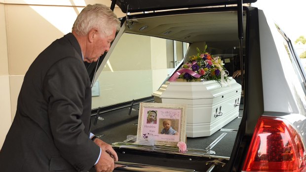 Peter Elberg of Peter Elberg Funerals places a photo and flower at the rear of the coffin.