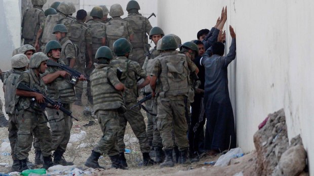 Turkish soldiers detain men near the Akcakale crossing gate between Turkey and Syria on Monday. From Syria, the men were suspected of being IS militants. 