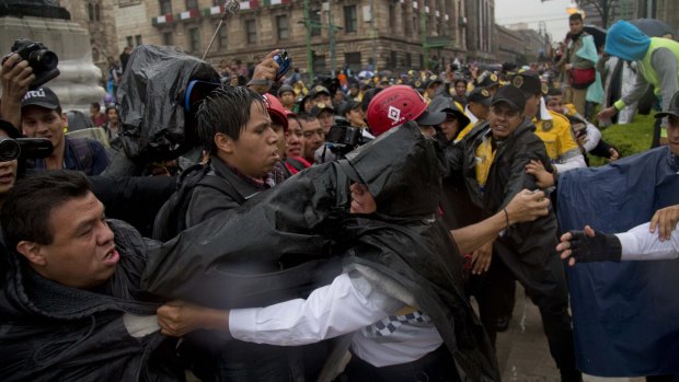 Police grab protesters after people broke shop windows in Mexico CIty during the march on Saturday to mark the anniversary of the disappearance of 43 student teachers. 