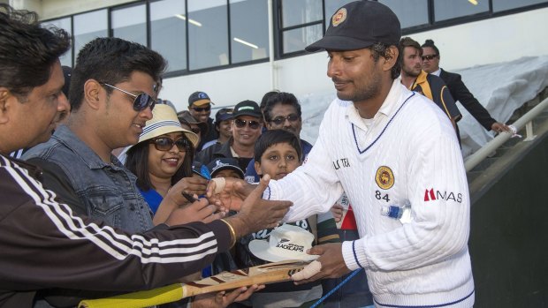 Sangakkara signs autographs for fans at the end of the day's play.