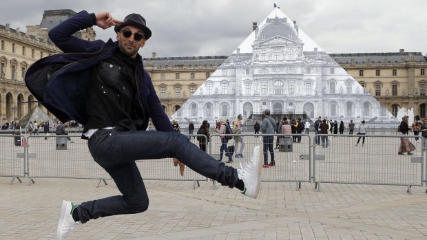 JR poses in front the Louvre Pyramid in Paris on Tuesday.