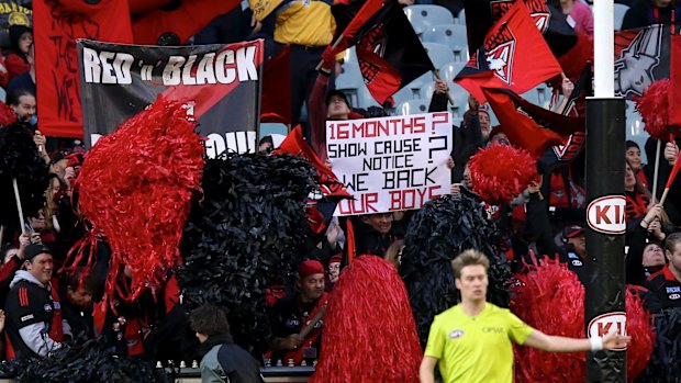 Essendon fans hold banners during a match against Melbourne last season referring to the problems the club has gone through.