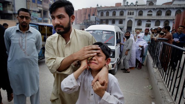 A man helps an injured boy to a hospital after an earthquake hit Peshawar, Pakistan on Sunday.