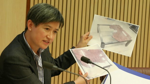 Senator Penny Wong brandishes photographic evidence of the damaged marble table during a hearing with the Finance and Public Administration committee.