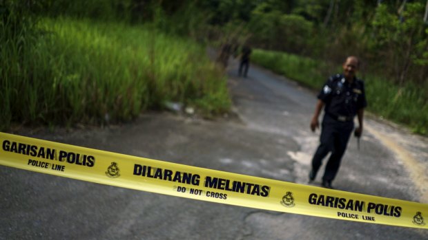 A Malaysian policeman leaves a site where human remains were found near an abandoned human trafficking camp in the jungle close to the Thai border in northern Malaysia.