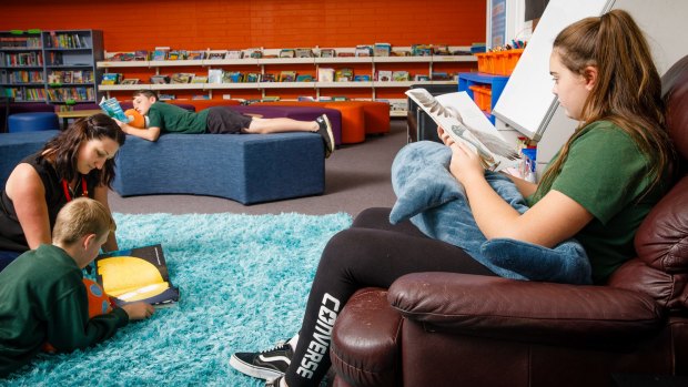 Charnwood Dunlop primary school librarian Bridgette Manley reads with sixth graders Tyreece Ryan (11), Cameron Morton (10), and Trista Buckley (11). The school says employed a teacher-librarian to help lift literacy levels.