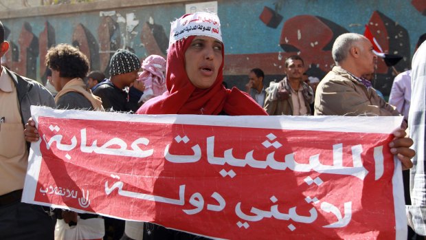 Yemenis shout slogans during a rally against the occupation of the capital by the Shiite Houthi movement. The woman's sign reads "militias are gangs that won't build a nation".