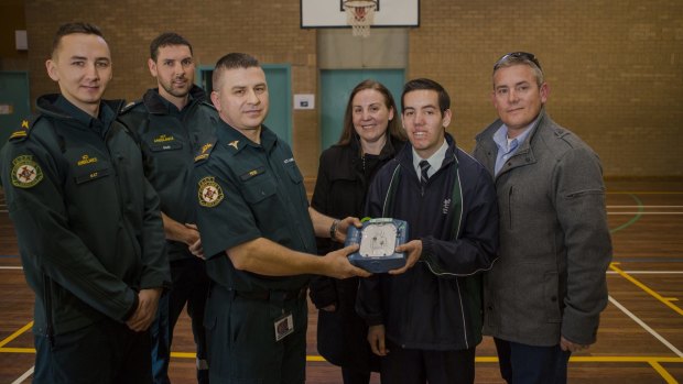 From left, call taker Matt Davis, and paramedics Sam Biddington and Peter Fraser are presented with a new defibrillator by Thomas Rowsell and his parents, Cheryl and Daniel.