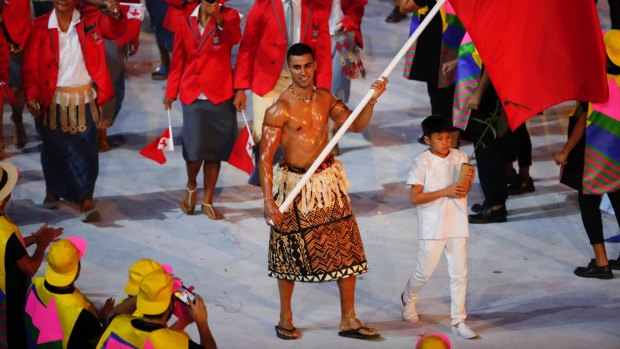 Pita Taufatofua carries the Tongan flag during the Parade of Nations for the opening ceremony of the 2016 Summer Olympics in Rio de Janeiro.