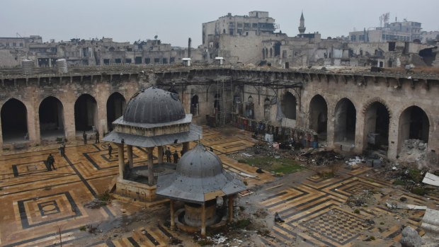 Syrian troops and pro-government gunmen marching walk inside the destroyed Grand Umayyad mosque in the old city of Aleppo.